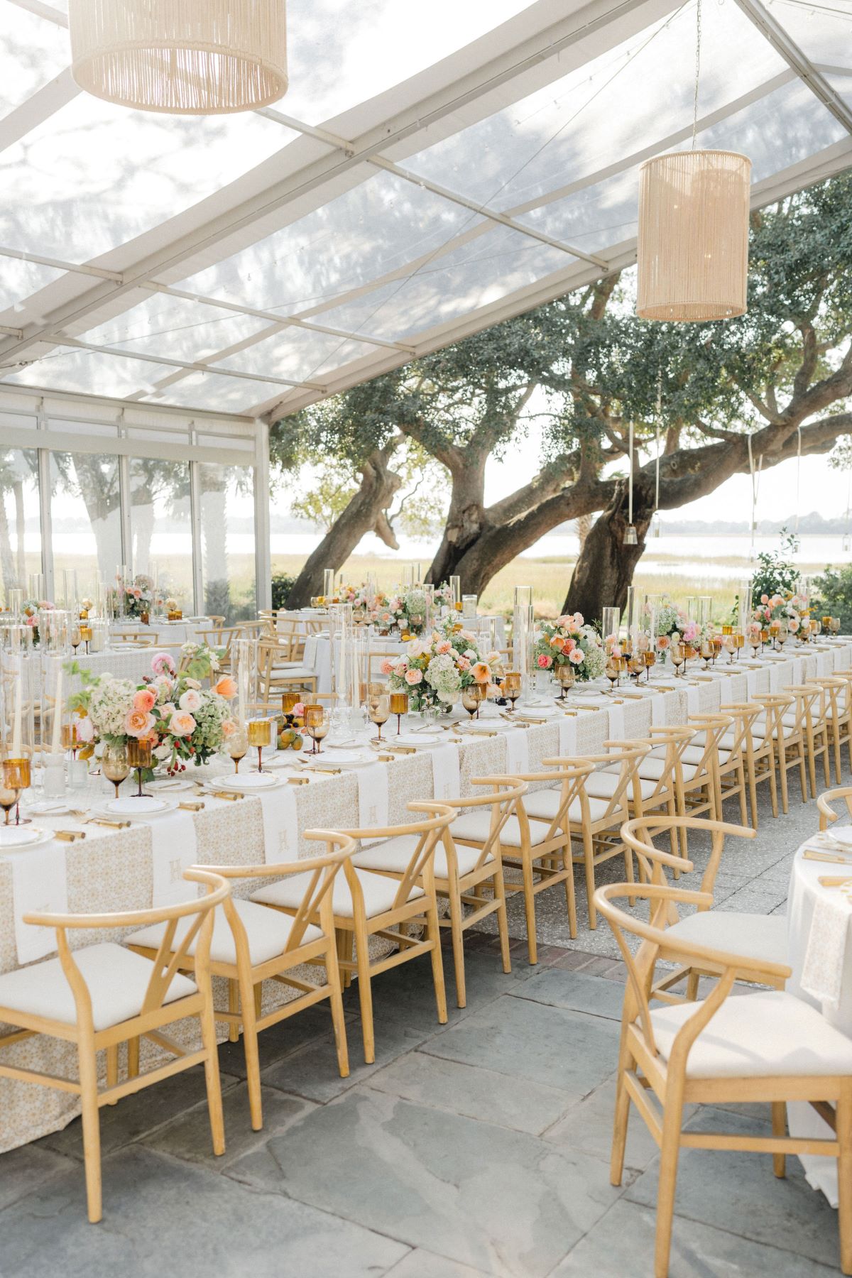 Elegant reception tables with wooden chairs, floral centerpieces, and refined place settings under a tent