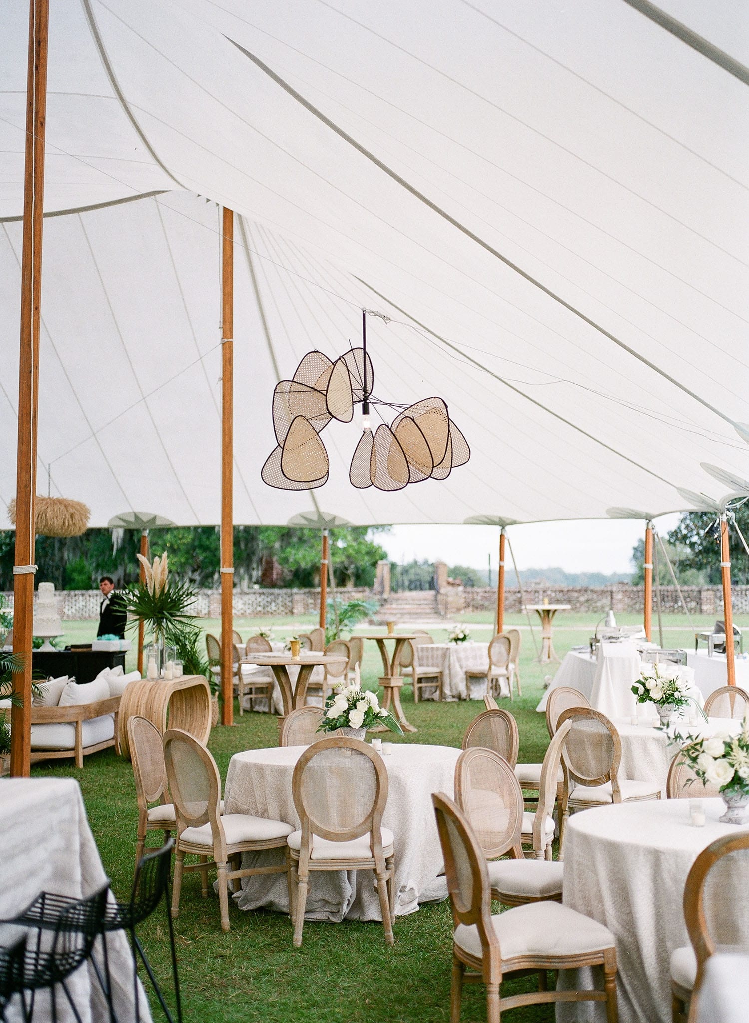 Sailcloth tent seating with upholstered round-back chairs and neutral-toned table settings | Curated Events Sailcloth tent seating with upholstered round-back chairs and neutral-toned table settings