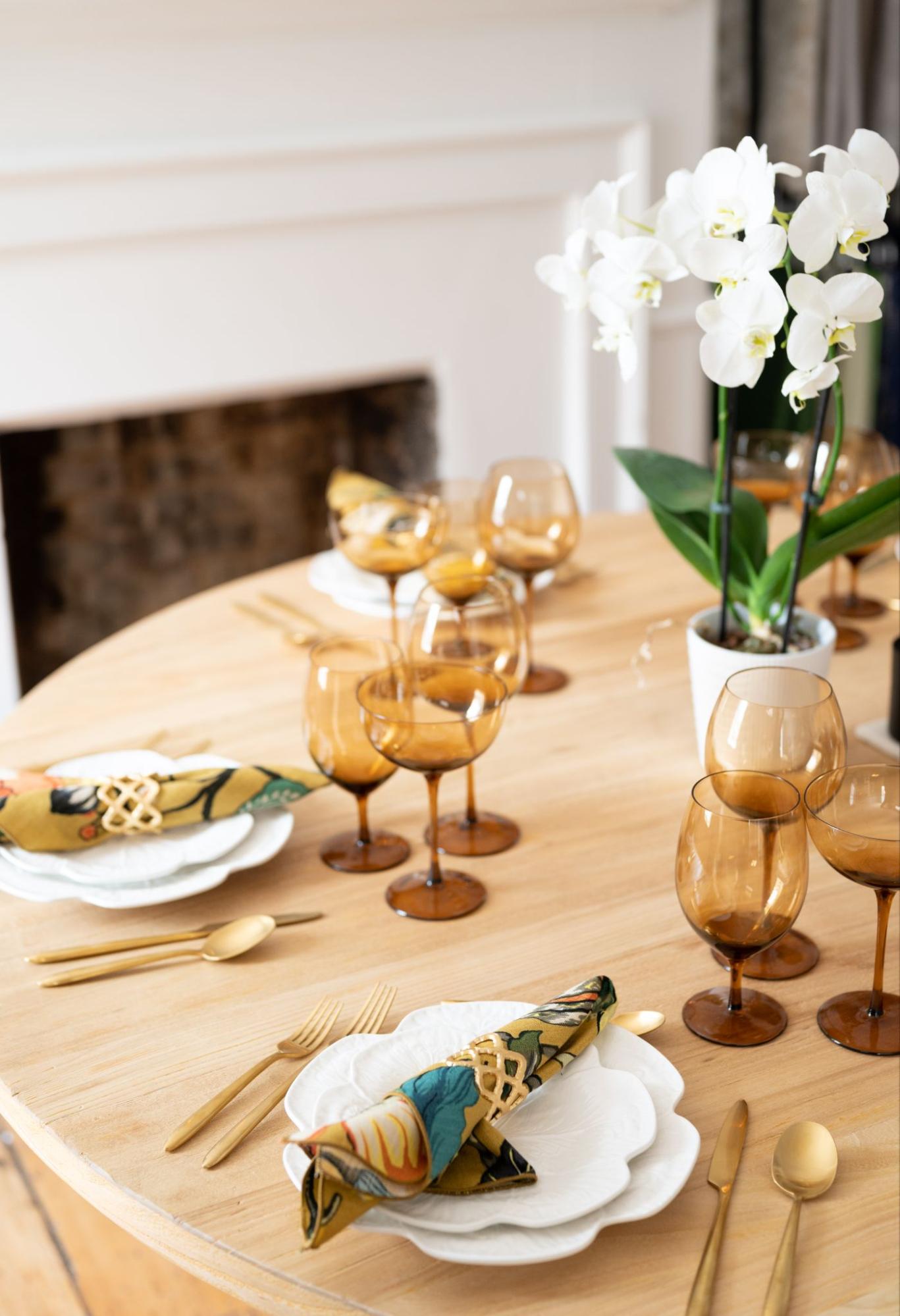 Corporate event table detail featuring amber glassware, gold flatware, and styled napkins.