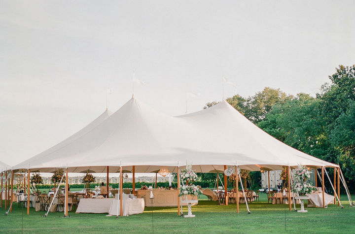 Large outdoor corporate event tent with fully arranged dining tables and professional event styling.
