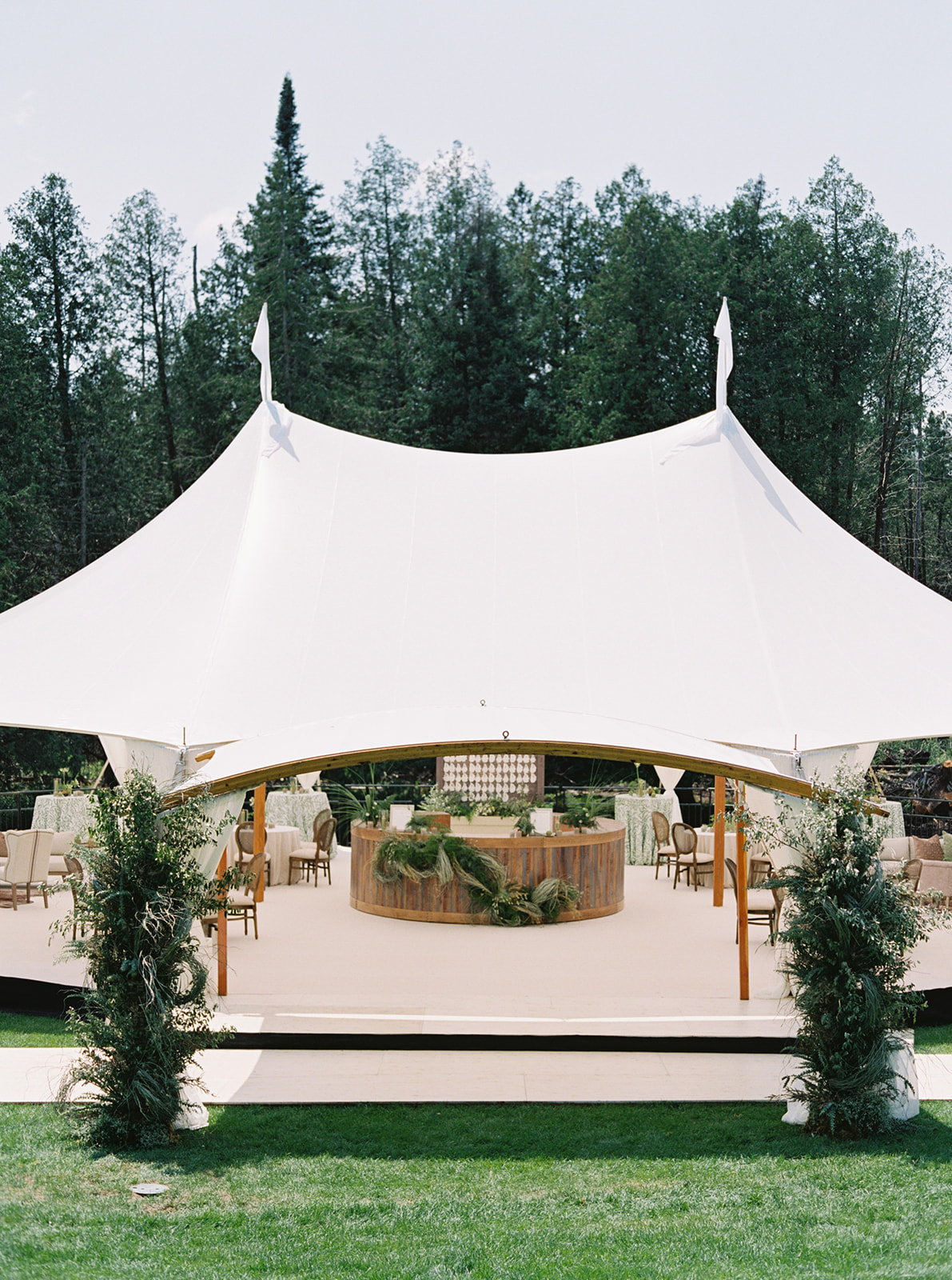 Corporate event tent bar setup with central service station and surrounding lounge seating. | Curated Events Elegant white event tent with table decor and greenery for corporate event rentals in Charlotte.