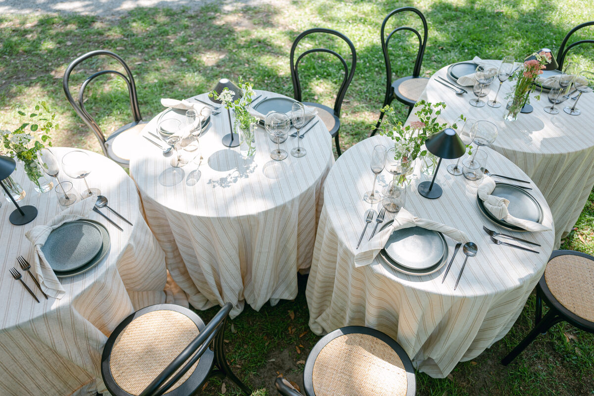 Round outdoor tables with striped linens and black lamps | Curated Events Round outdoor tables with striped linens and black lamps