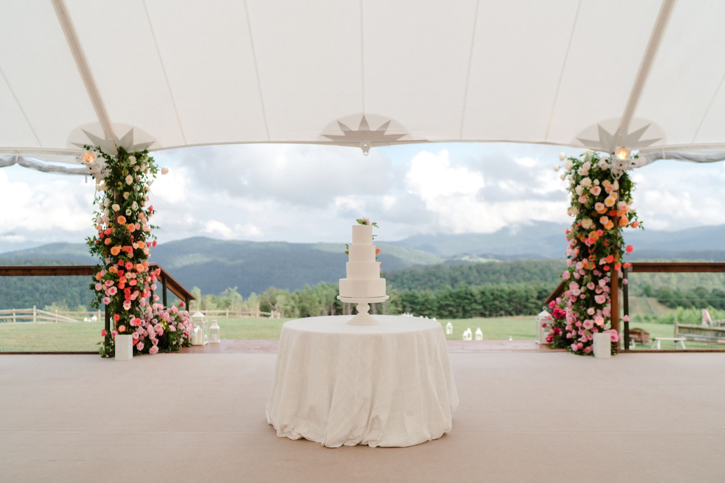 Wedding cake displayed under a sailcloth tent with mountain views.