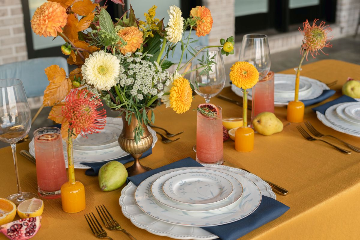 Bright yellow summer event table with citrus drinks, blue napkins, and floral centerpiece. | Curated Events Bright yellow summer event table with citrus drinks, blue napkins, and floral centerpiece.