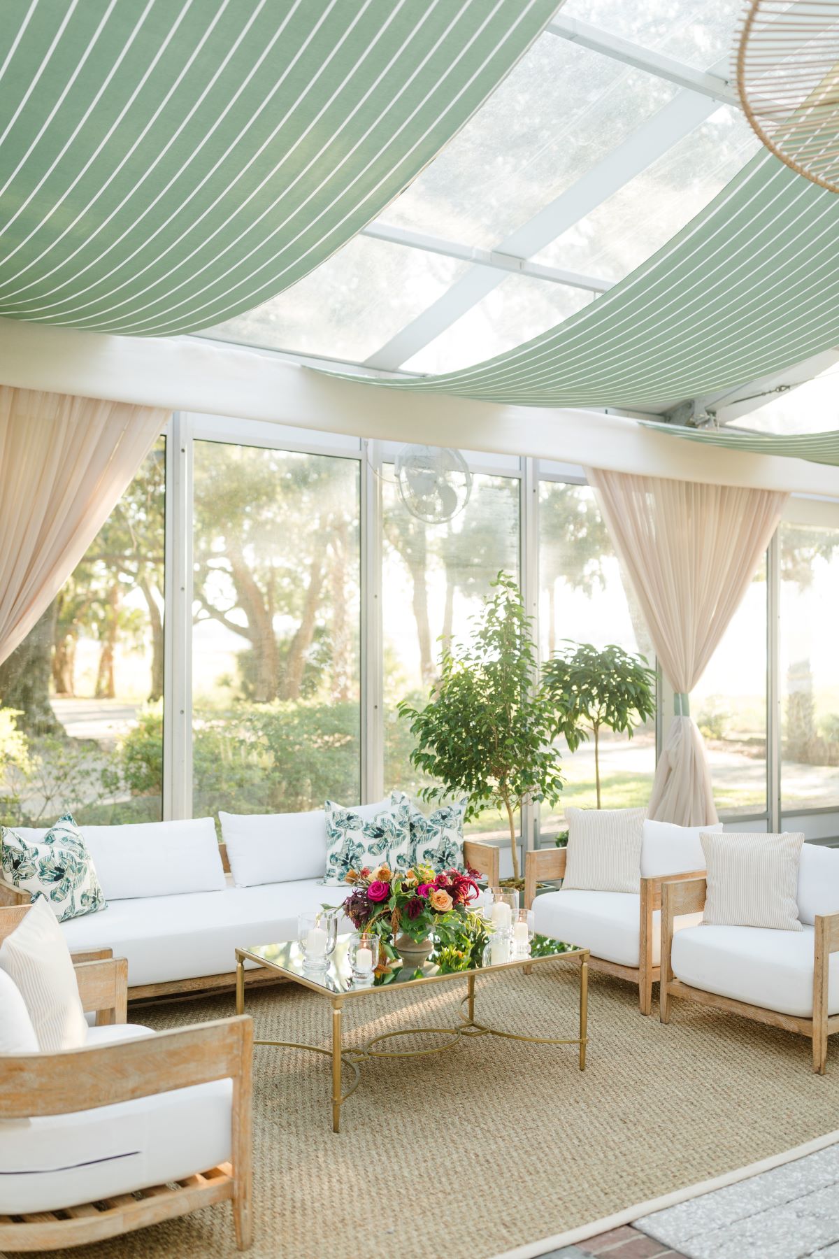 Bright clear span tent lounge with pale green ceiling draping and white seating.