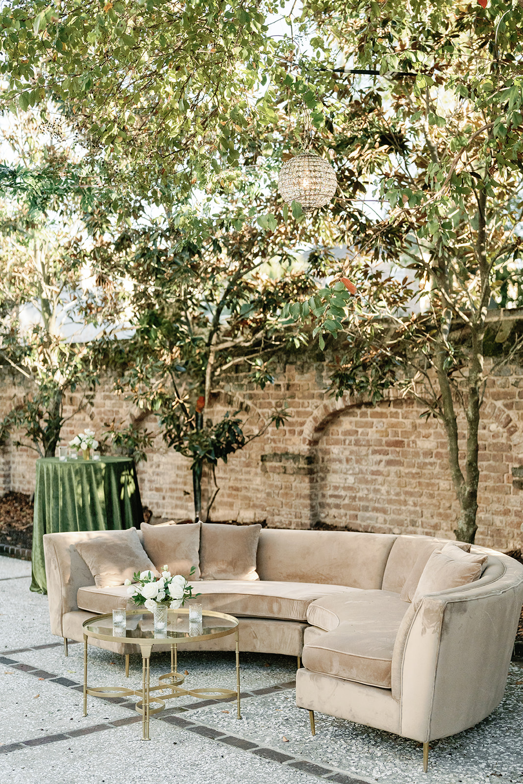 Beige outdoor lounge sofa with glass table and floral accents.