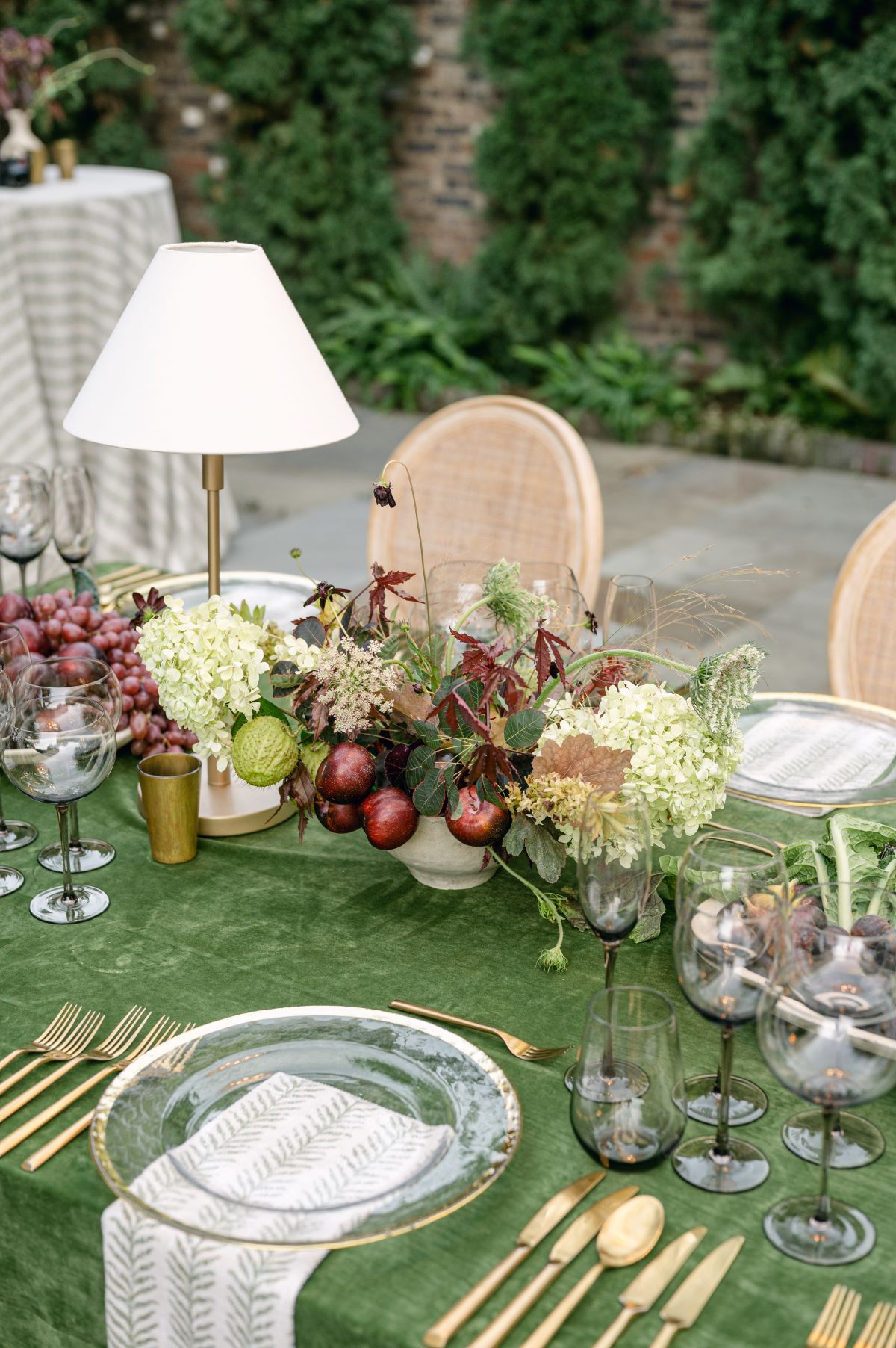 Green outdoor tablescape with fruit, florals, smoked glassware, and gold flatware. | Curated Events Green outdoor tablescape with fruit, florals, smoked glassware, and gold flatware.