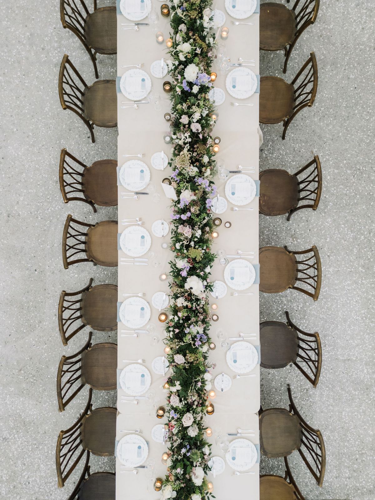 Overhead view of a long reception table with floral garland and place settings.