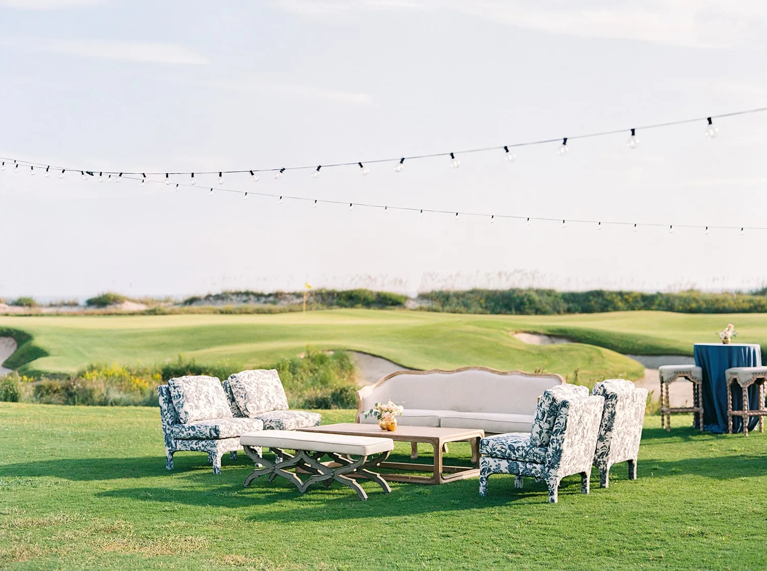 Blue patterned chairs and a white sofa arranged on a lawn