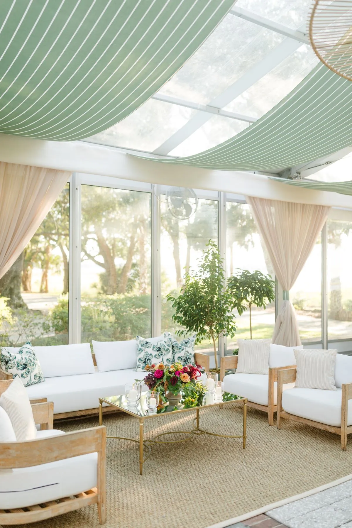 White lounge furniture beneath green draping in a clear-top tent
