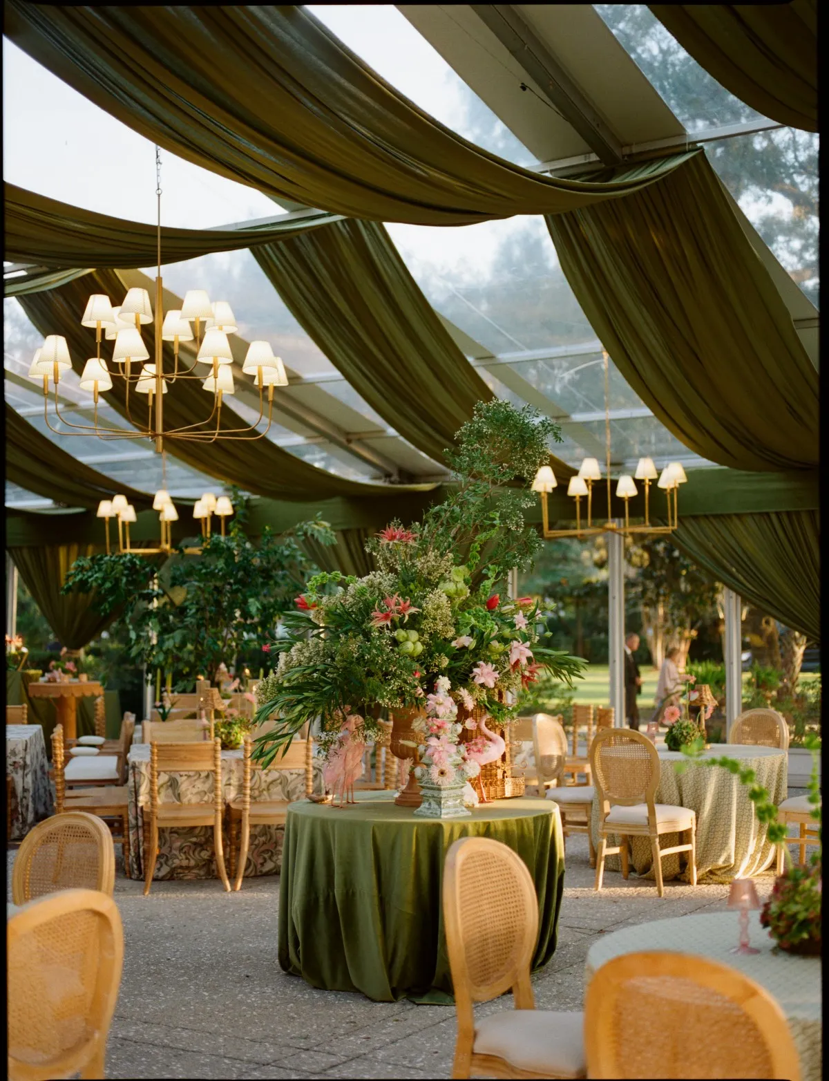 Green-draped reception tent with chandeliers and an olive velvet table