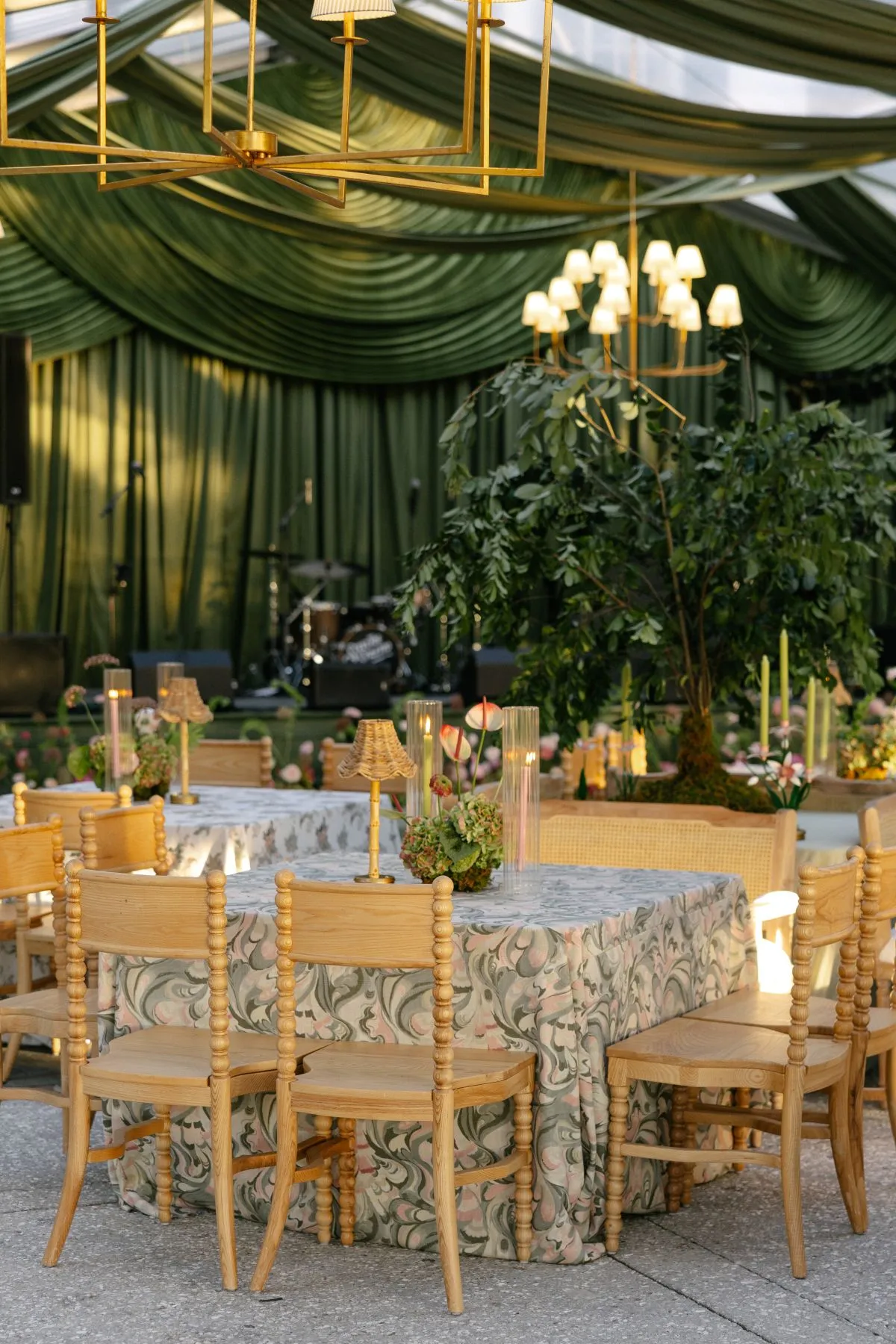 Patterned reception table beneath green draping and chandeliers