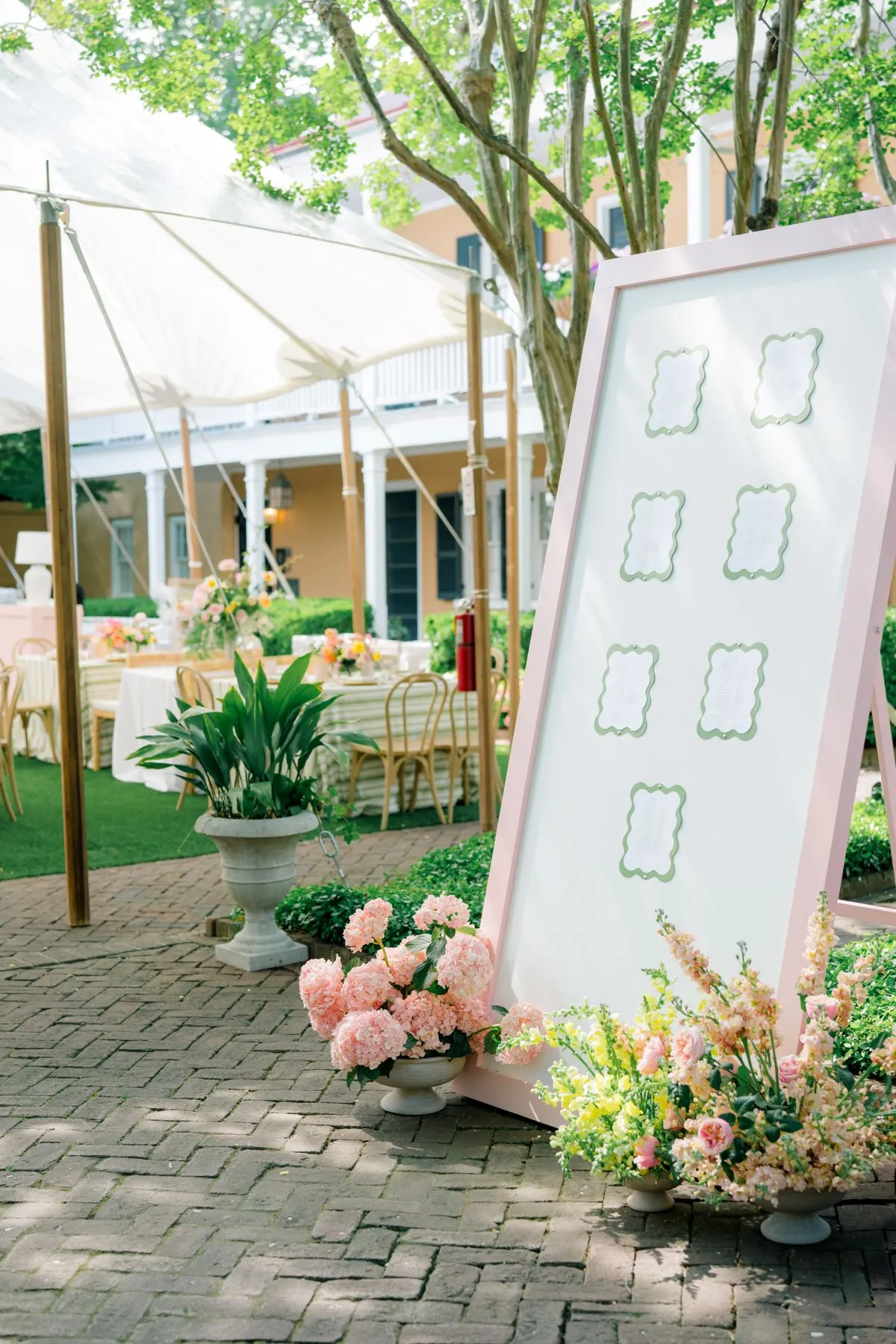 Floral seating chart beside a garden reception tent