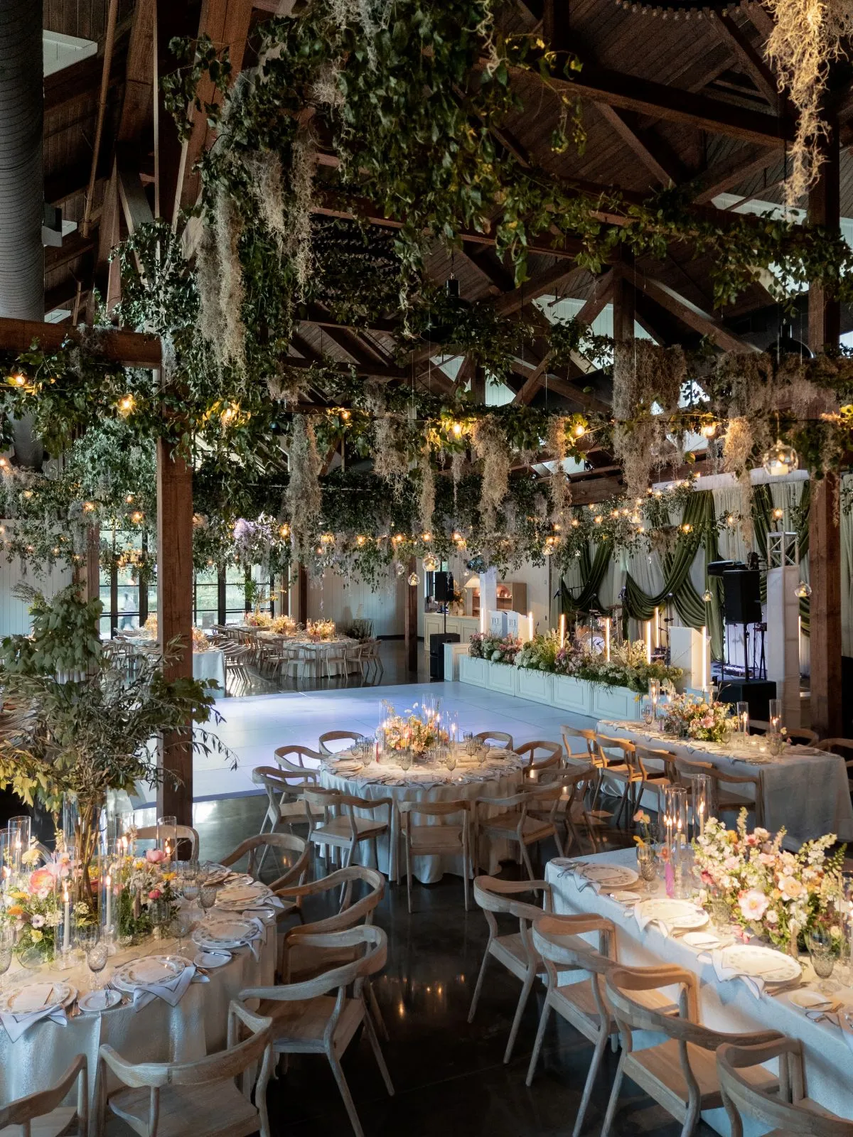 Greenery-filled reception with a white dance floor and dining tables