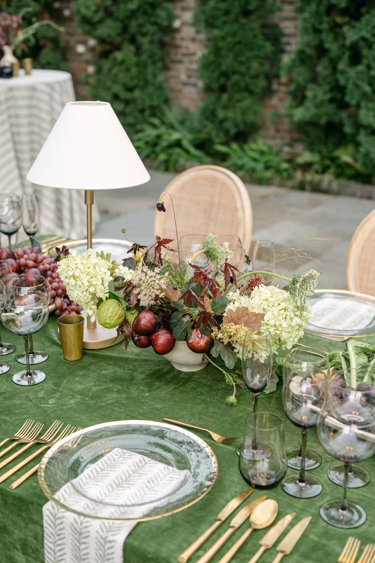 Green velvet dining table with autumn florals and gold flatware