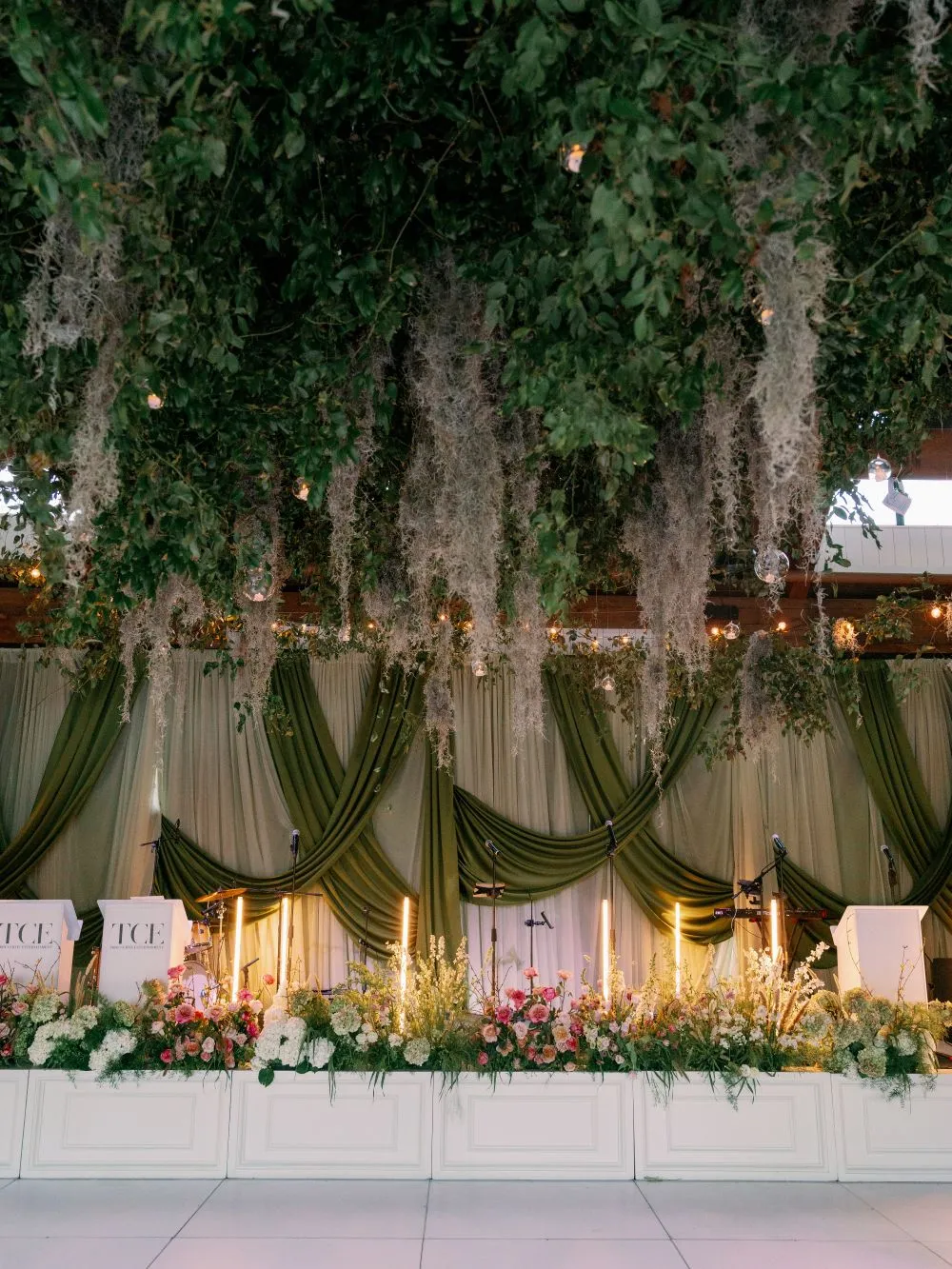 Wedding stage with green draping and hanging greenery