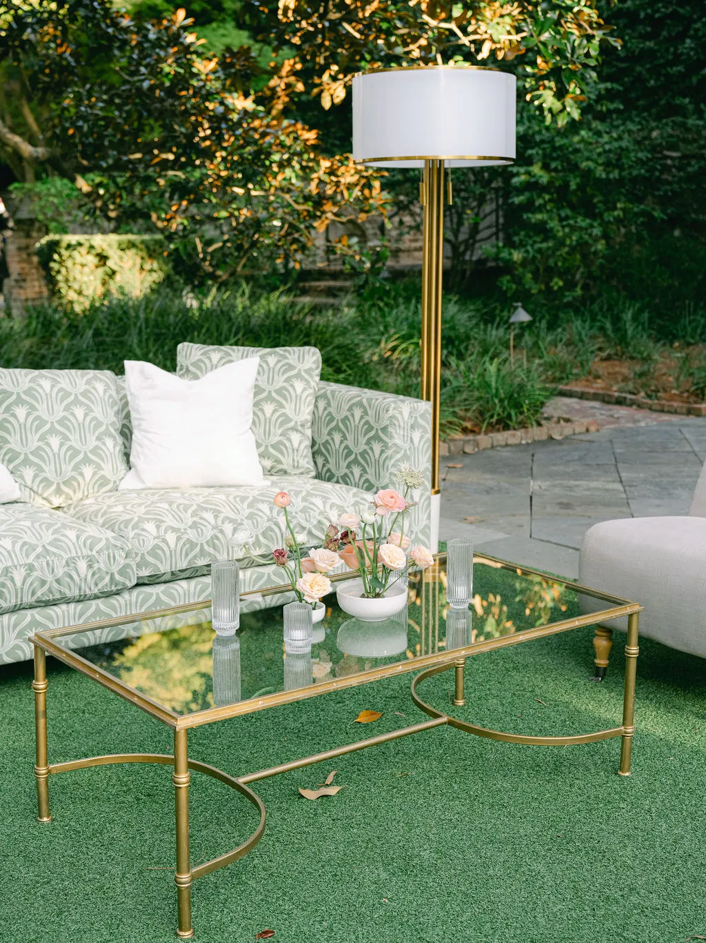 Green patterned sofa and brass coffee table in a garden lounge