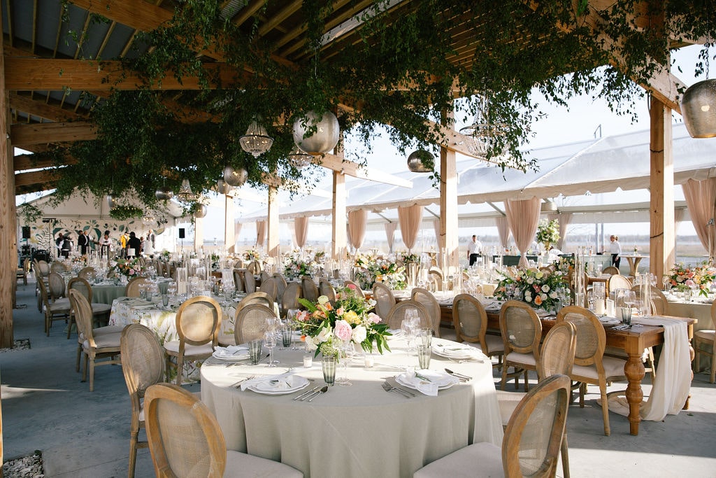 Summer event dining setup with round tables, rental chairs, and greenery accents
