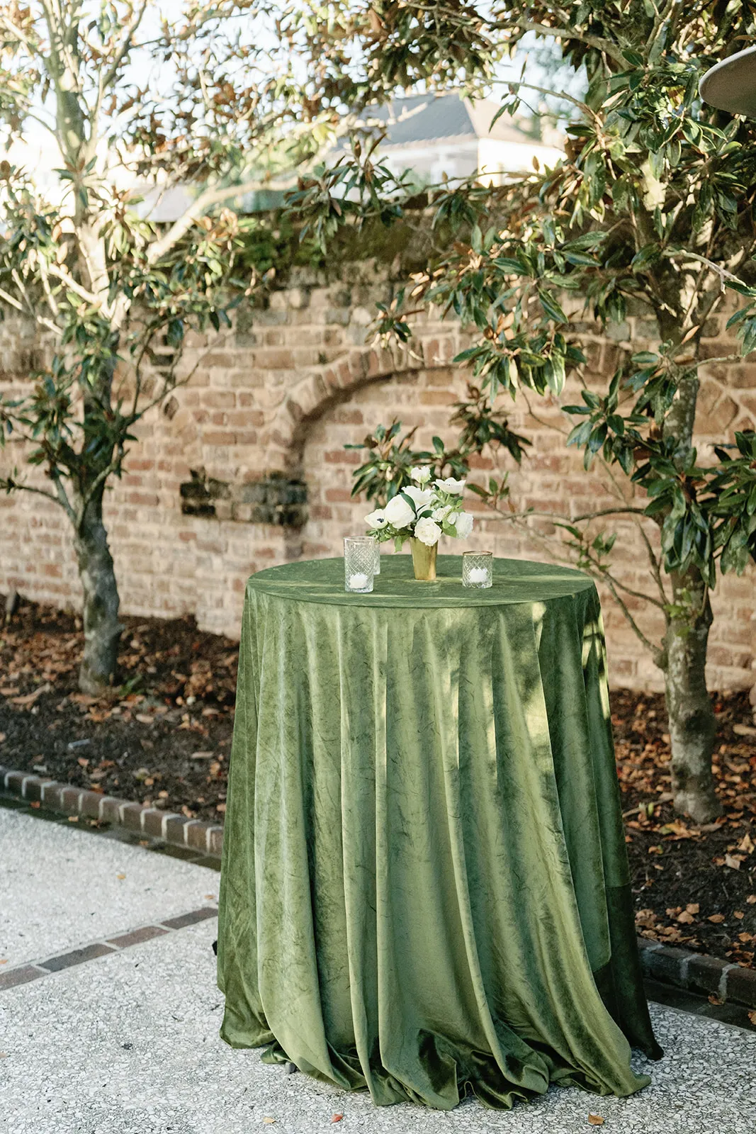 Green velvet cocktail table in a brick courtyard