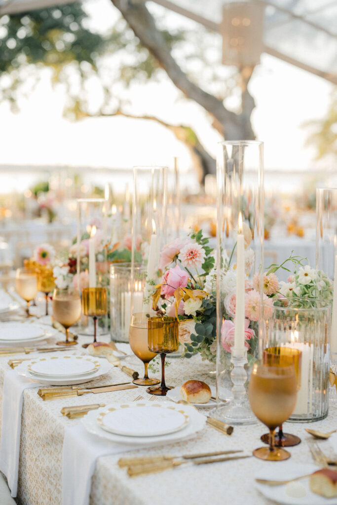 Elegant outdoor dining setup with floral arrangements, candles, and gold accents.