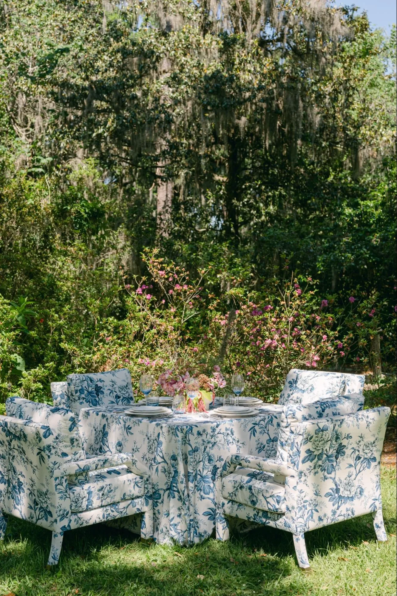 Blue floral armchairs surrounding a matching round table in an outdoor wedding garden