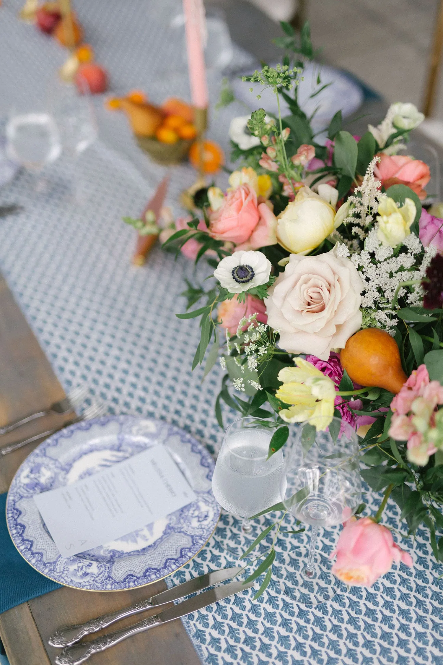 Blue-and-white place setting with patterned linen and a colorful floral centerpiece