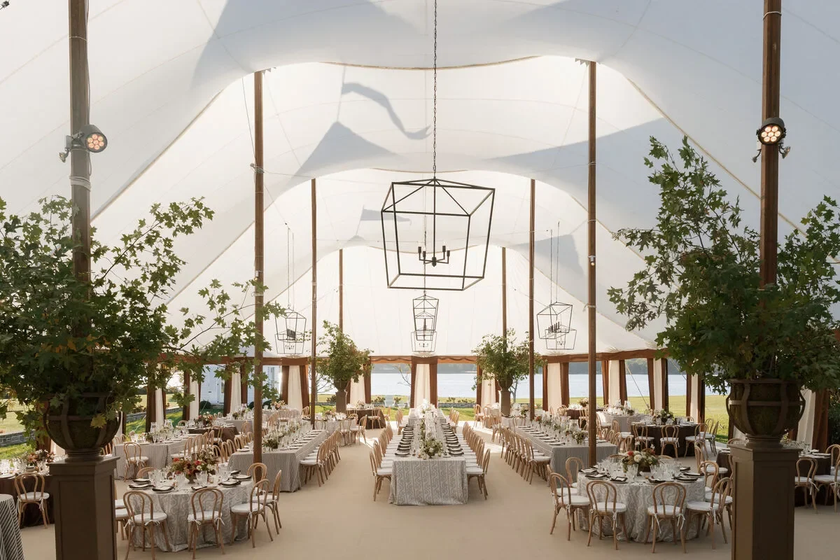 Sailcloth wedding tent with banquet tables, geometric chandeliers, and potted trees