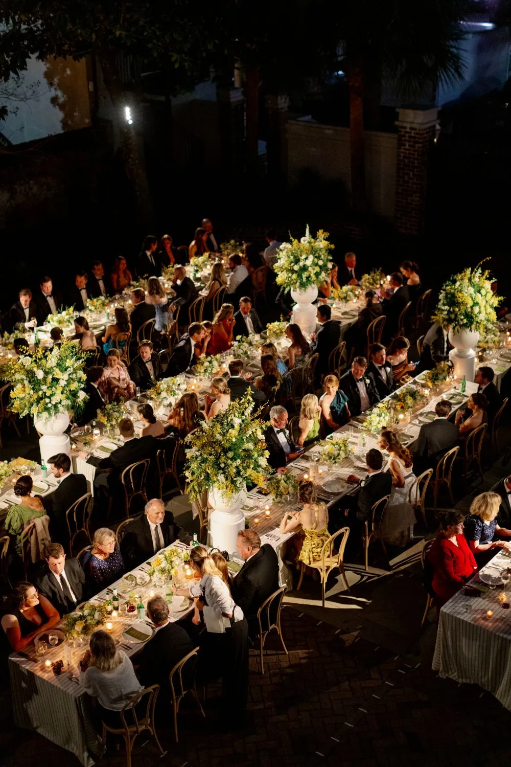 Overhead view of formal gala guests seated at long candlelit dinner tables with floral centerpieces