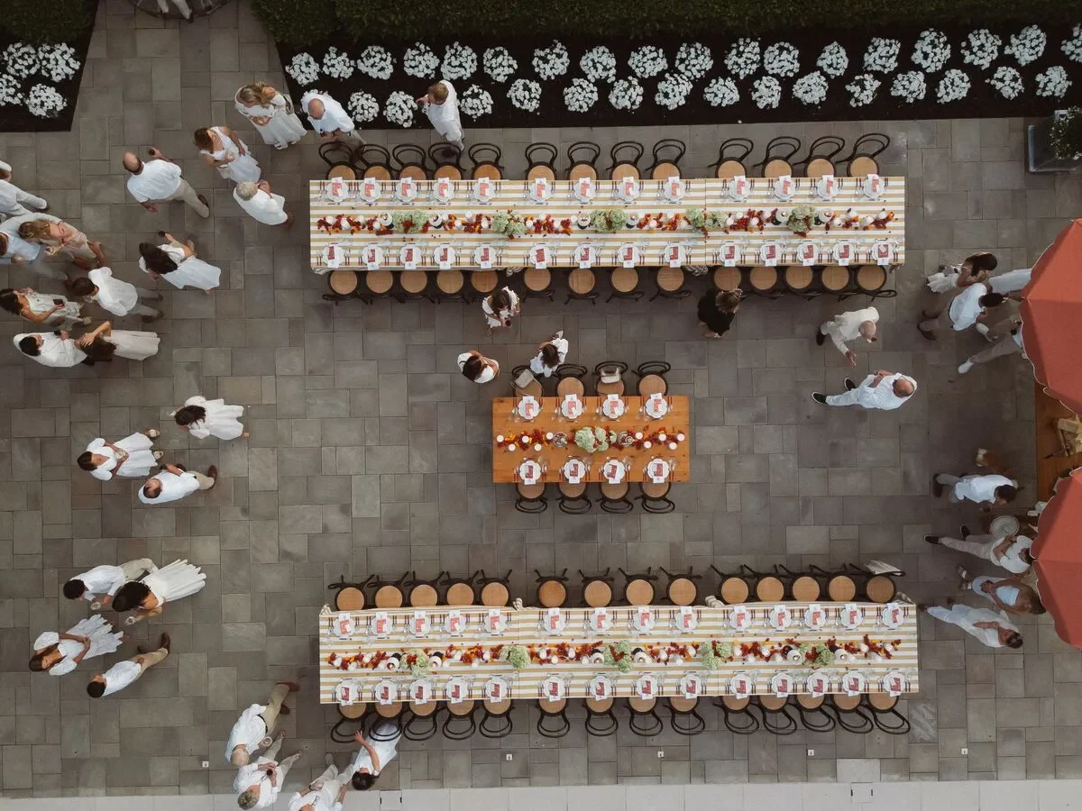 Overhead view of long outdoor wedding tables with floral centerpieces and place settings Overhead view of long outdoor wedding tables with floral centerpieces and place settings