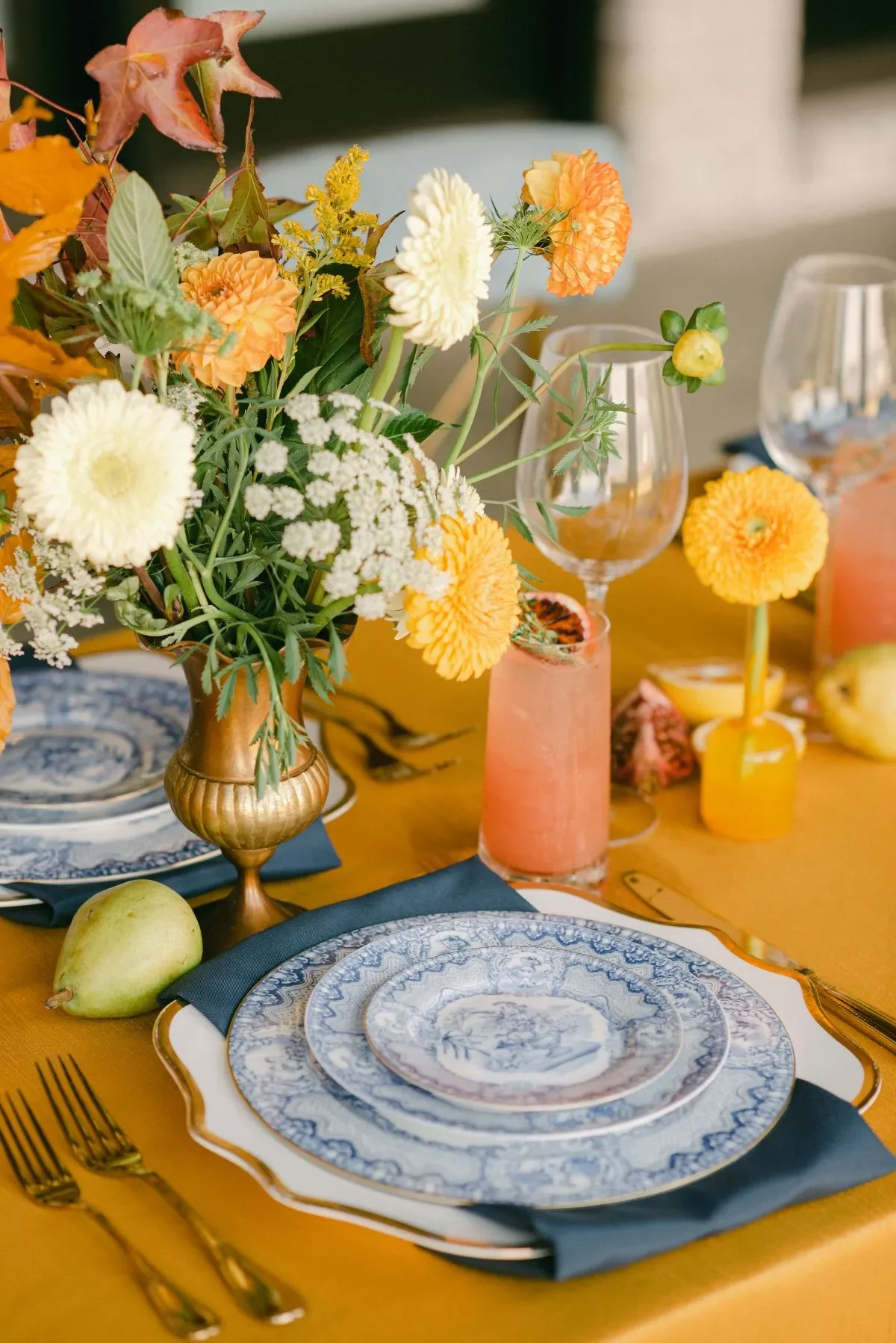Fall wedding place setting with mustard linen, blue china, orange flowers, and gold flatware Fall wedding place setting with mustard linen, blue china, orange flowers, and gold flatware