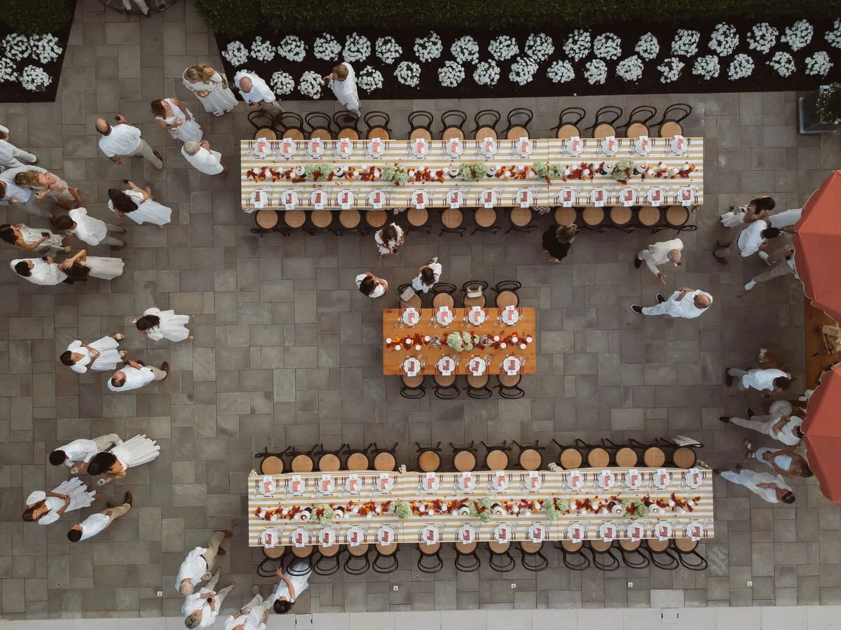 Aerial view of long banquet tables with coordinated place settings and floral decor in a courtyard