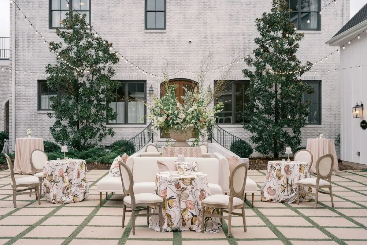 Wedding courtyard lounge with white sofas, floral cocktail tables, and a large centerpiece