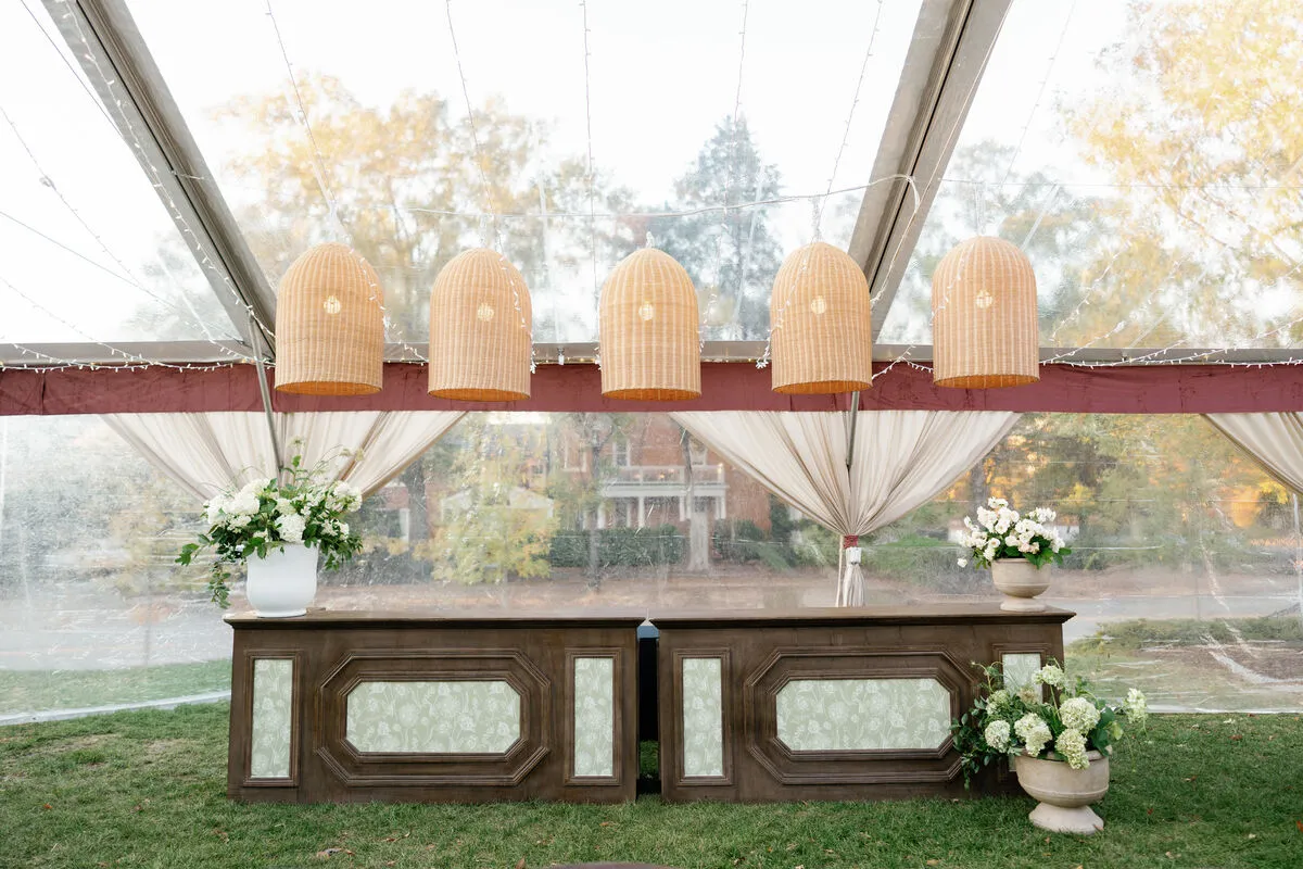 Rows of wooden ceremony chairs beside pink and white floral arrangements
