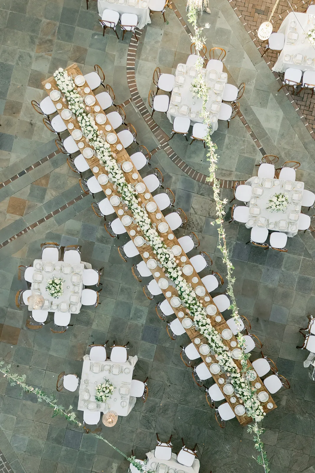 Overhead view of formal outdoor dining tables arranged across a stone terrace | Curated Events Overhead view of formal outdoor dining tables arranged across a stone terrace